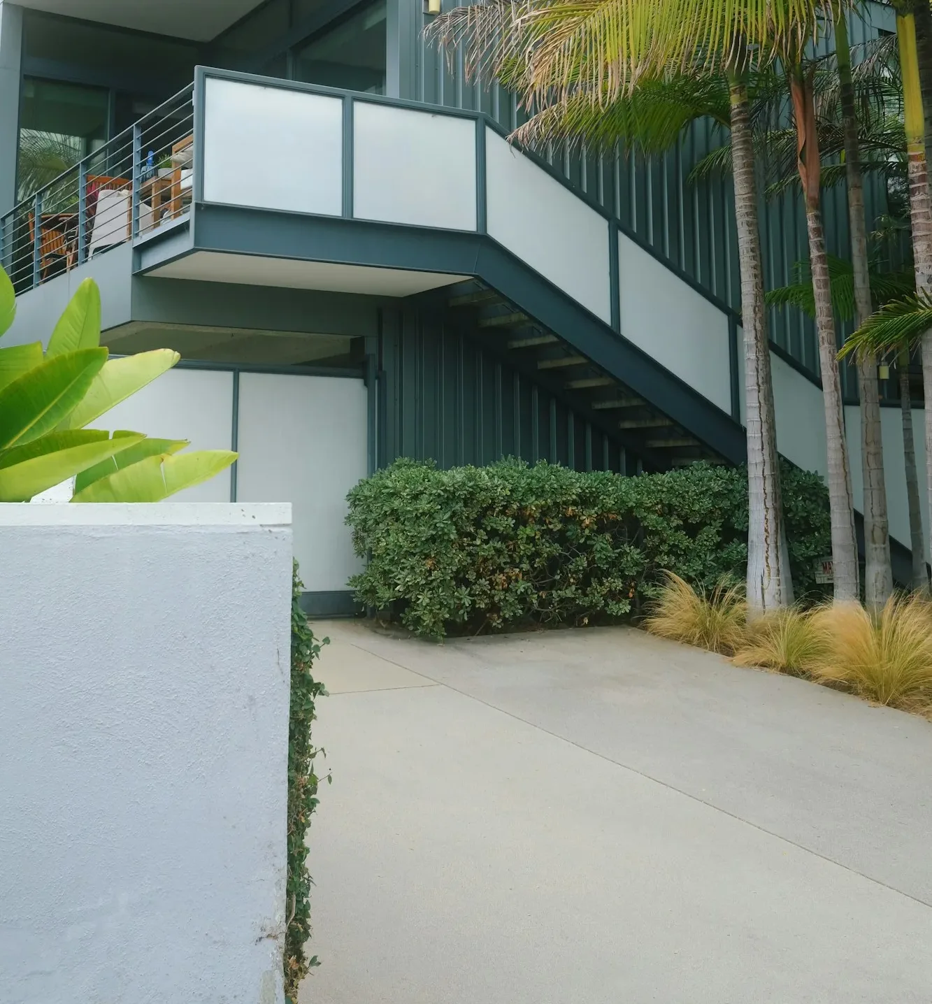 a building with a balcony and palm trees in front of it